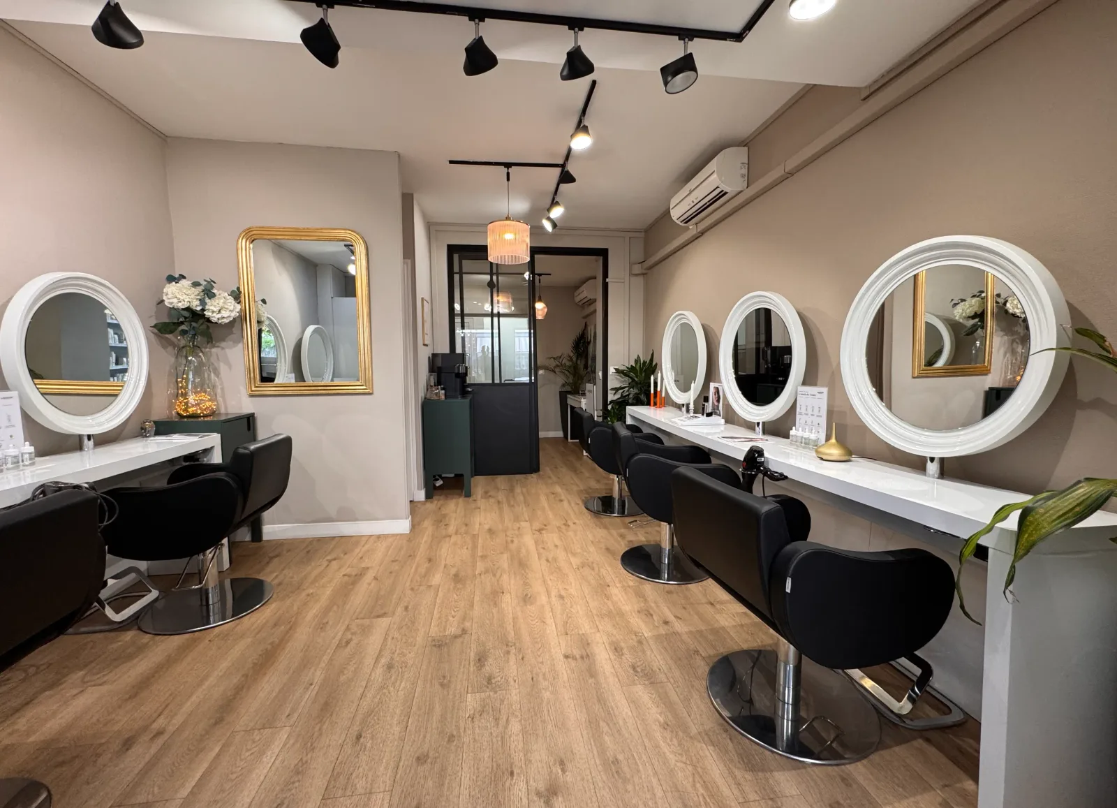L'intérieur du salon Julie Salmonie à Royan : miroirs ronds, fauteuils noirs et touches dorées dans un cadre lumineux